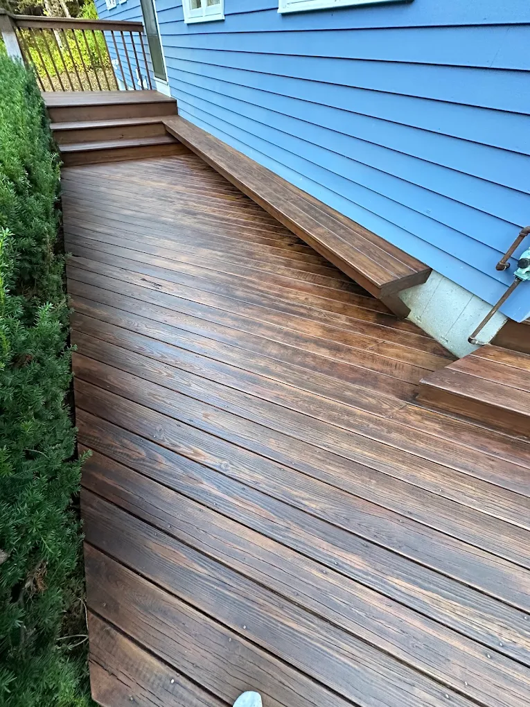 Freshly stained wood deck and bench against blue siding