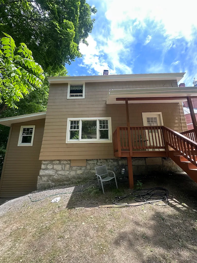 Two-story home with tan shingle siding and a stained deck