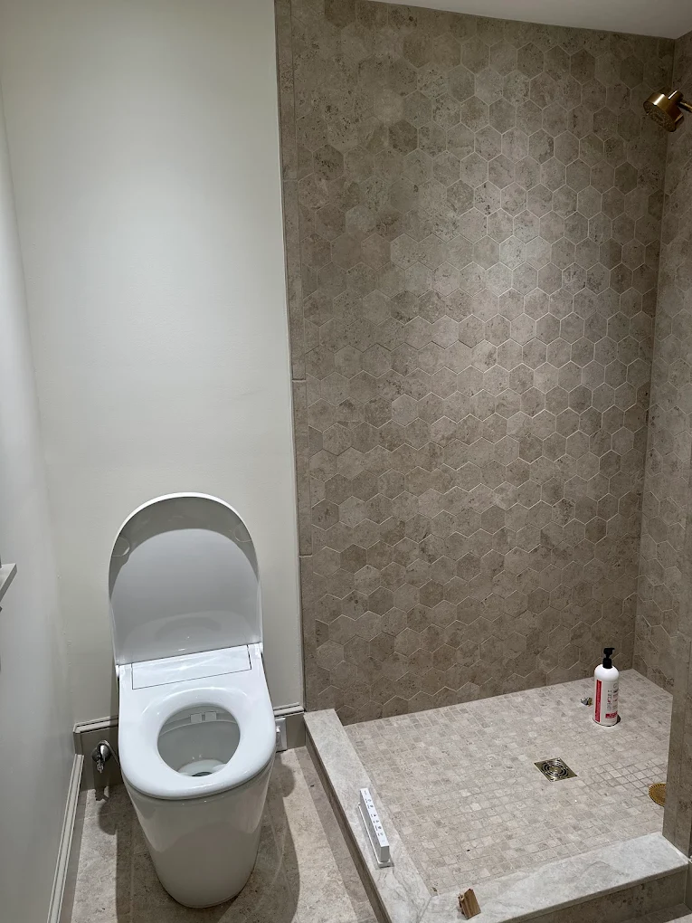 Bathroom with soft white walls beside a hexagon-tile shower