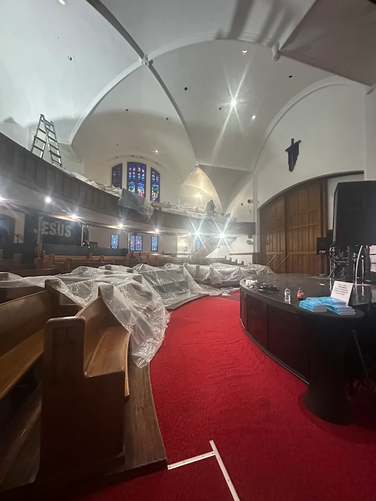 Church sanctuary with pews covered in plastic during ceiling work