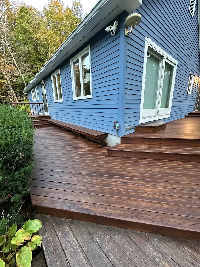 Blue home exterior beside a freshly restored wraparound deck