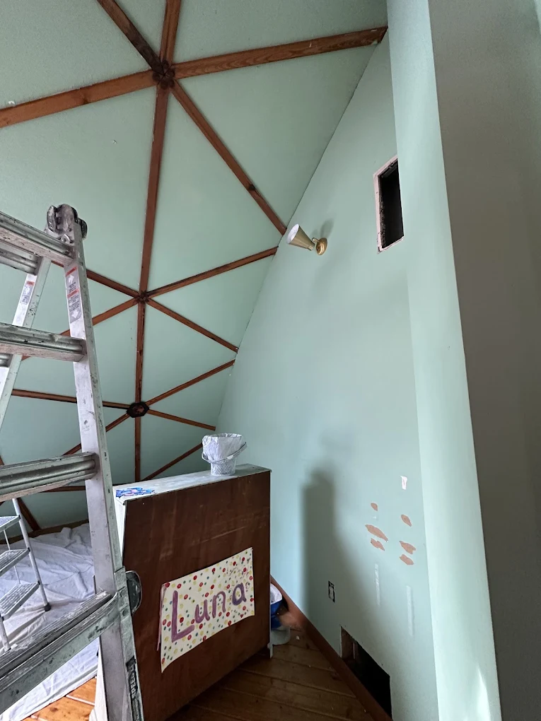 Geodesic dome room with mint walls and a ladder set for painting