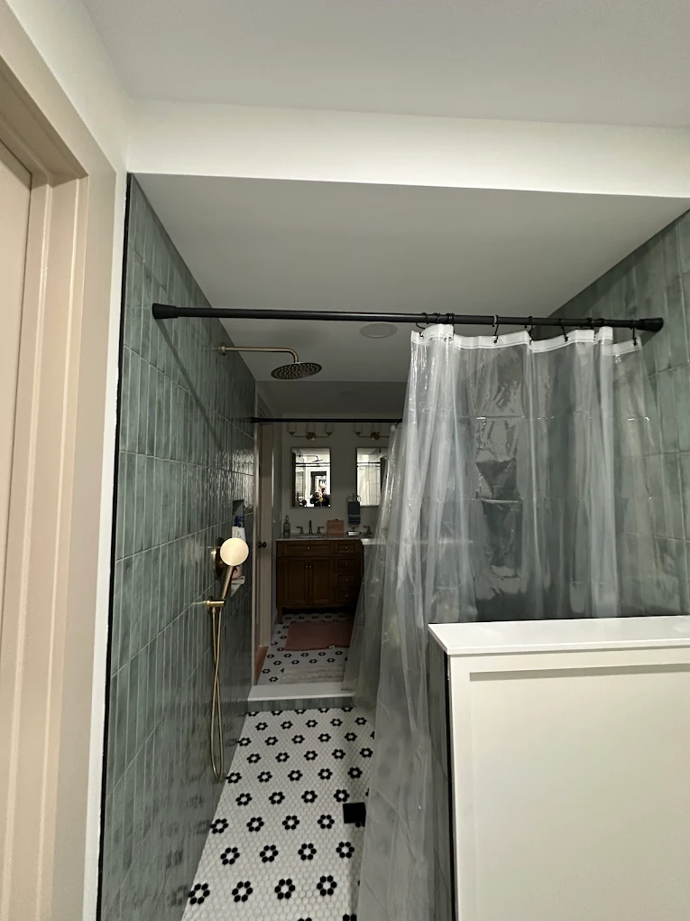 Finished bathroom with white ceiling and green tiled shower