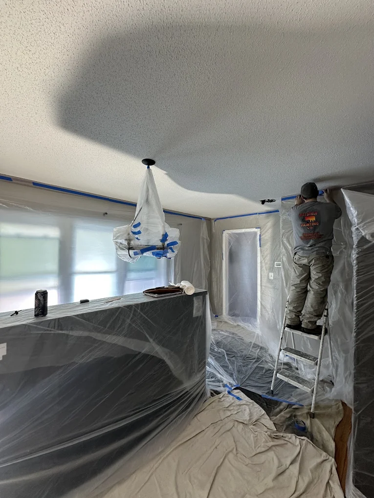 Painter working in a room fully protected with plastic and drop cloths