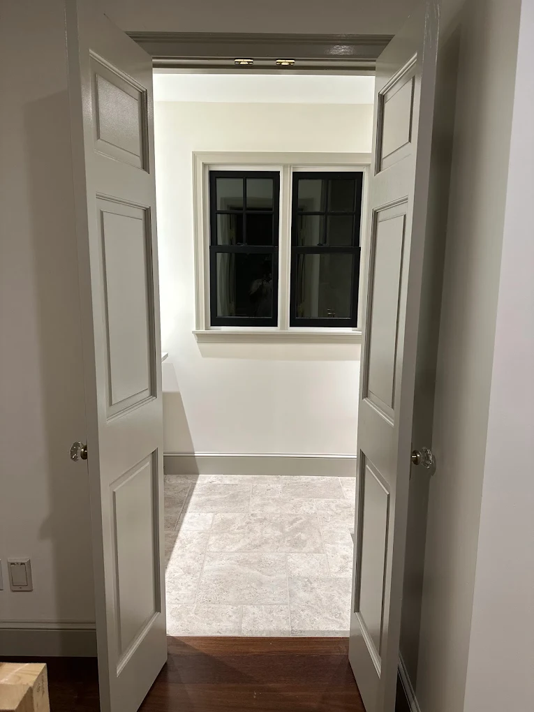 Fresh white room viewed through gray paneled double doors