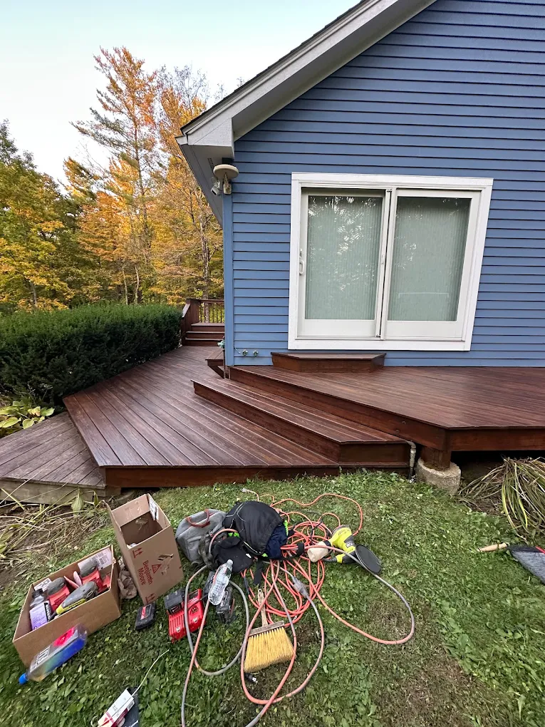 Blue home with a freshly stained wraparound deck