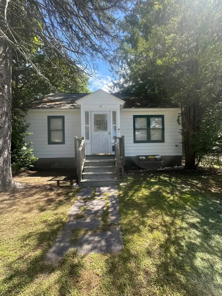 White cottage with green window trim and a fresh exterior