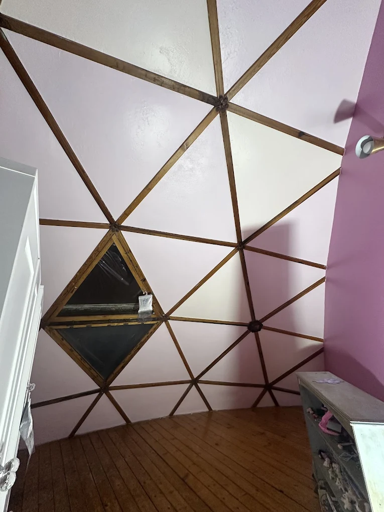 Finished geodesic dome with pink wall panels and wood beams