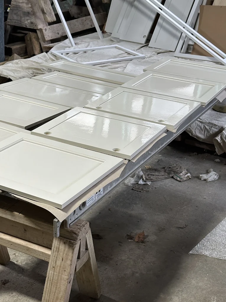 Freshly painted white cabinet doors drying on work tables