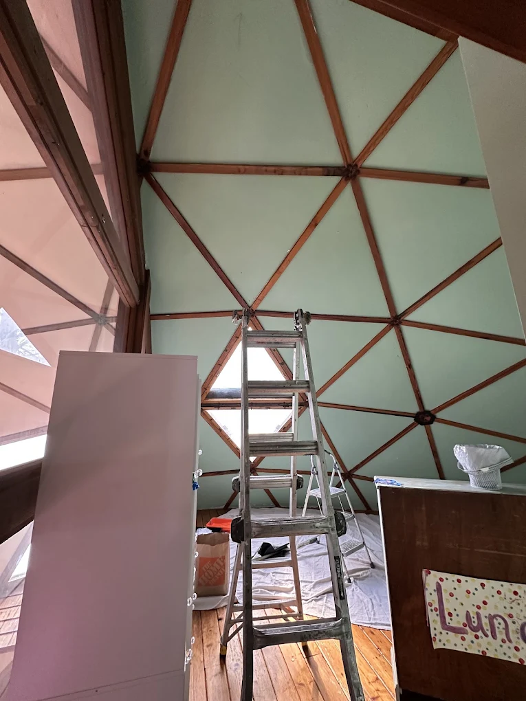 Ladder set up inside a geodesic dome with green panels