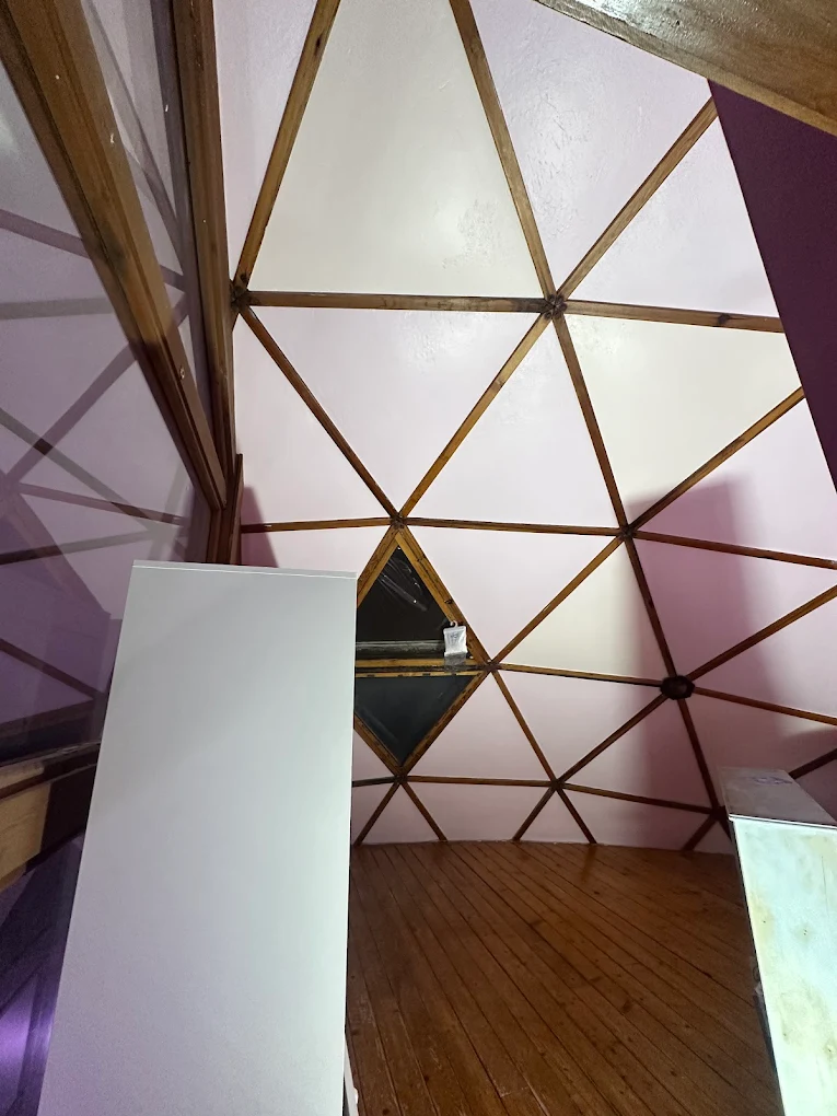 Geodesic dome interior with soft pink panels and wood beams