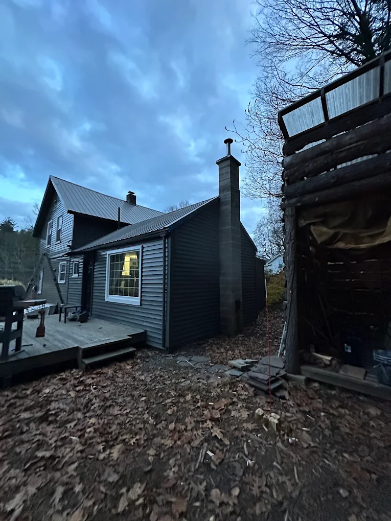 Dark gray home with metal roof and deck at dusk