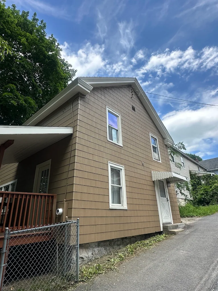 Tan shingle-sided home with fresh white window trim
