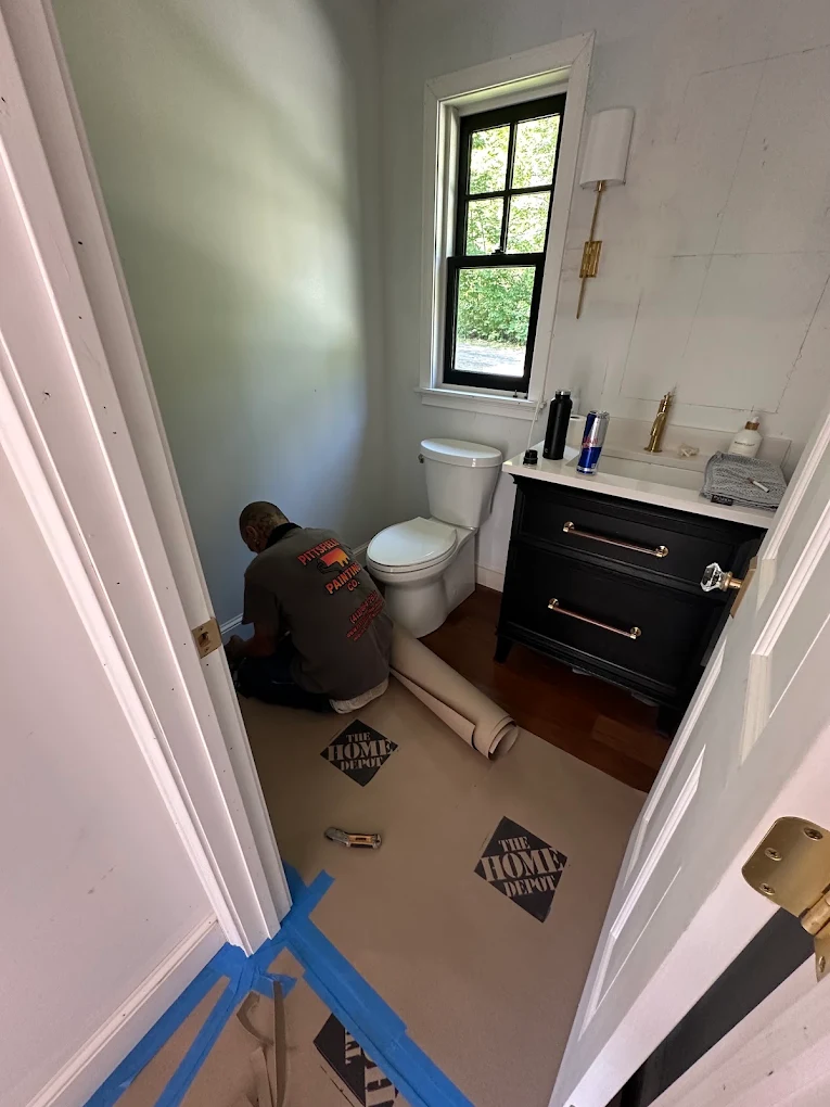 Painter laying floor protection in a powder room before work